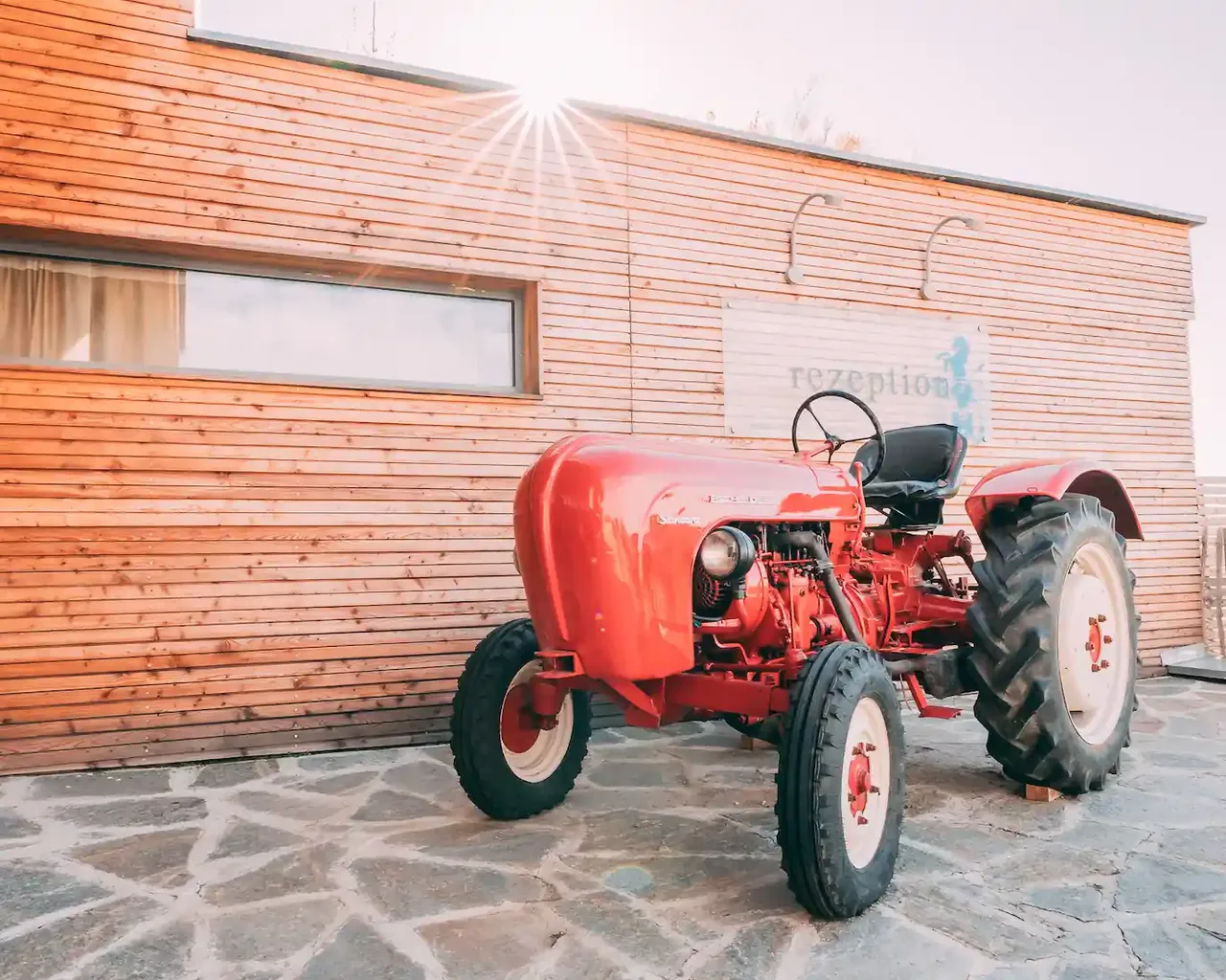 Červený traktor před recepcí Gut Hügle