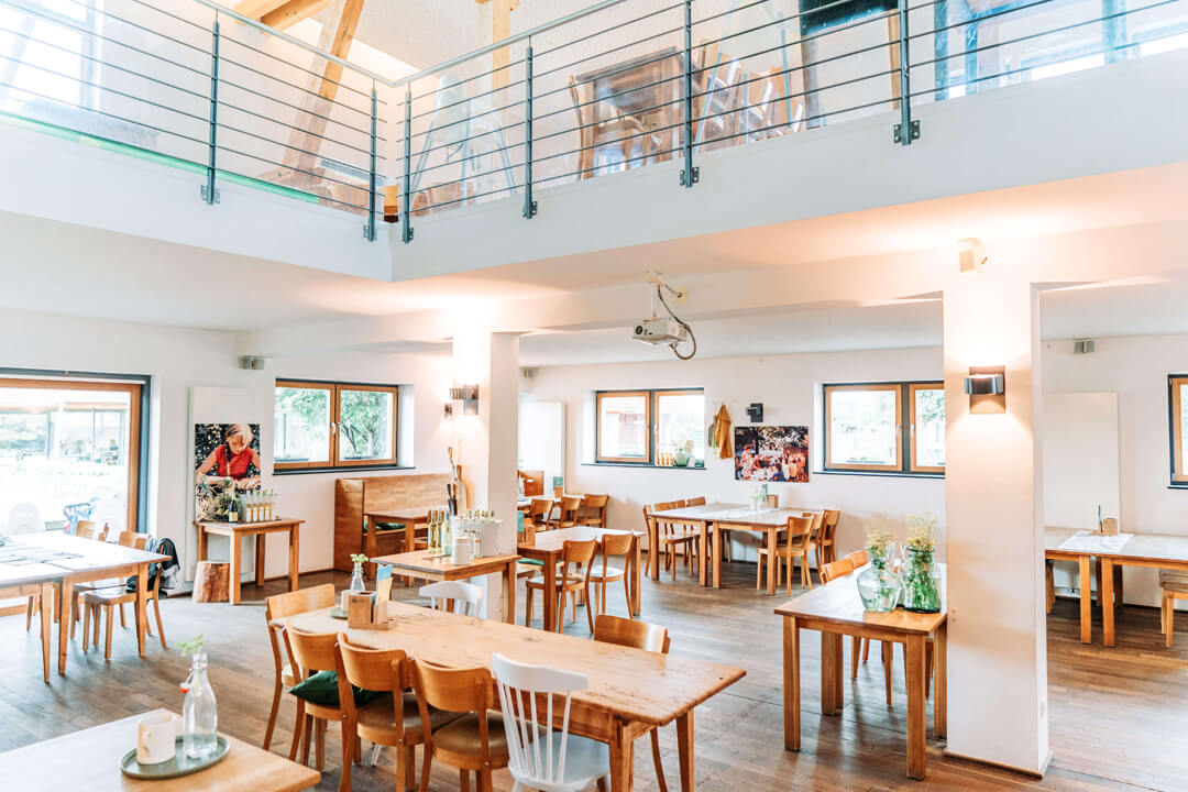Světlý prostor restaurace s dřevěnými stoly na Gut Hügle